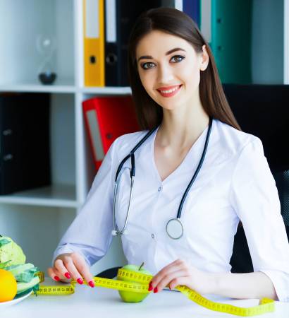 Health. Diet and Healthy Nutrition. Doctor Dietitian Holding in Hands Fresh Green Apple and Centimeter Ribbon. Smiles Beautiful and Young Doctor in the Light Room. High Resolution Health. Diet and Healthy Nutrition. Doctor Dietitian Holding in Hands Fresh Green Apple and Centimeter Ribbon. Smiles Beautiful and Young Doctor in the Light Room. High Resolution